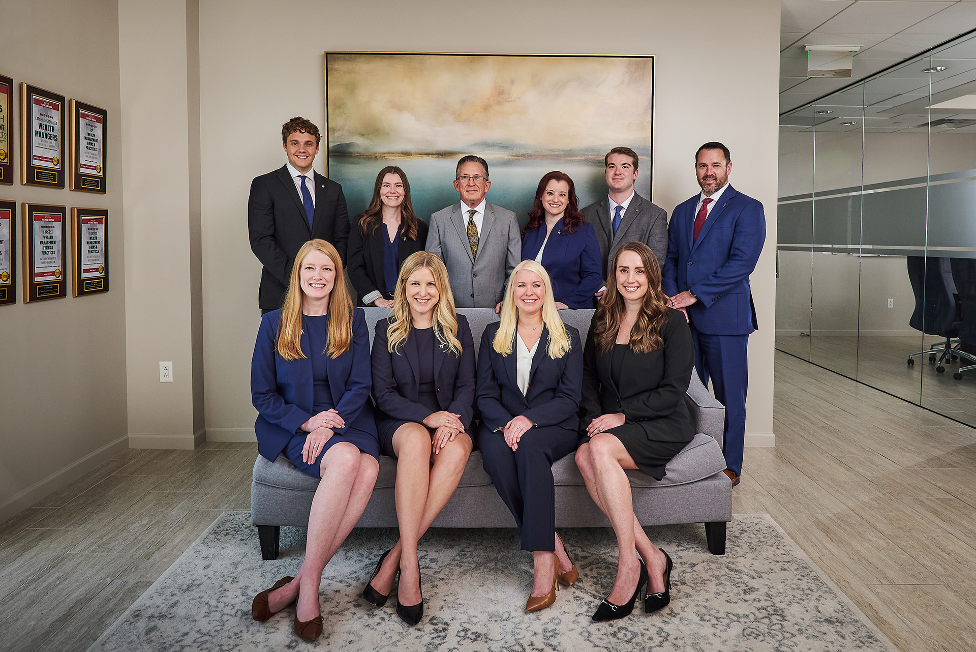 Professional team of ten financial advisors posing together in modern office, wealth management firm staff photo
